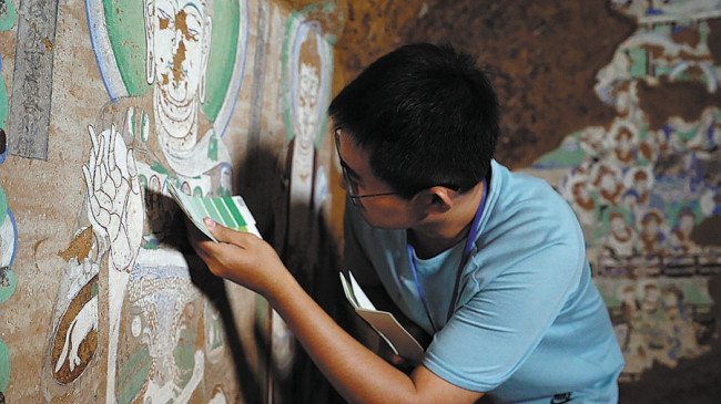 Ο Χαν Μαογιουάν έχει ένα χρωματικό διάγραμμα για να προσδιορίσει τις αποχρώσεις των χρωμάτων σε μια τοιχογραφία στο Σπήλαιο Α-άι στην αυτόνομη περιοχή Σιντζιάνγκ Ουιγκούρ. [Η φωτογραφία παρέχεται στην China Daily]