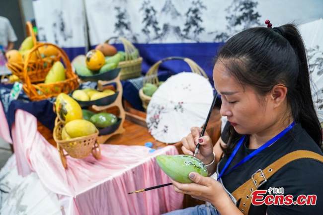 Ζωγραφίζοντας ένα μάνγκο στην έκθεση που πραγματοποιήθηκε στο Μπαϊσέ της επαρχίας Γκουανγκσί στις 18 Ιουλίου 2021. (Φωτογραφία / China News Service)